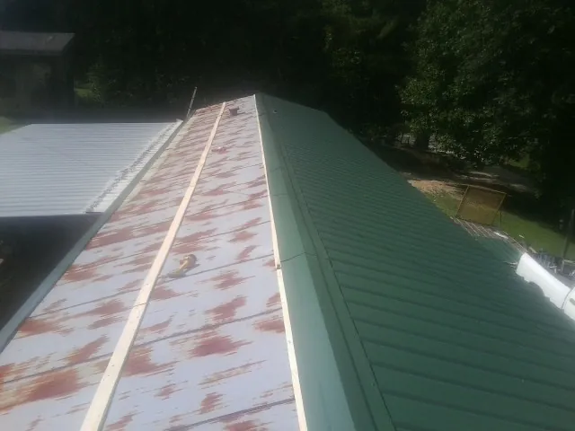 Old rusted panels beside newly installed green metal roofing — Wind Damage Roof Repair by Roofing Brothers in Myersville