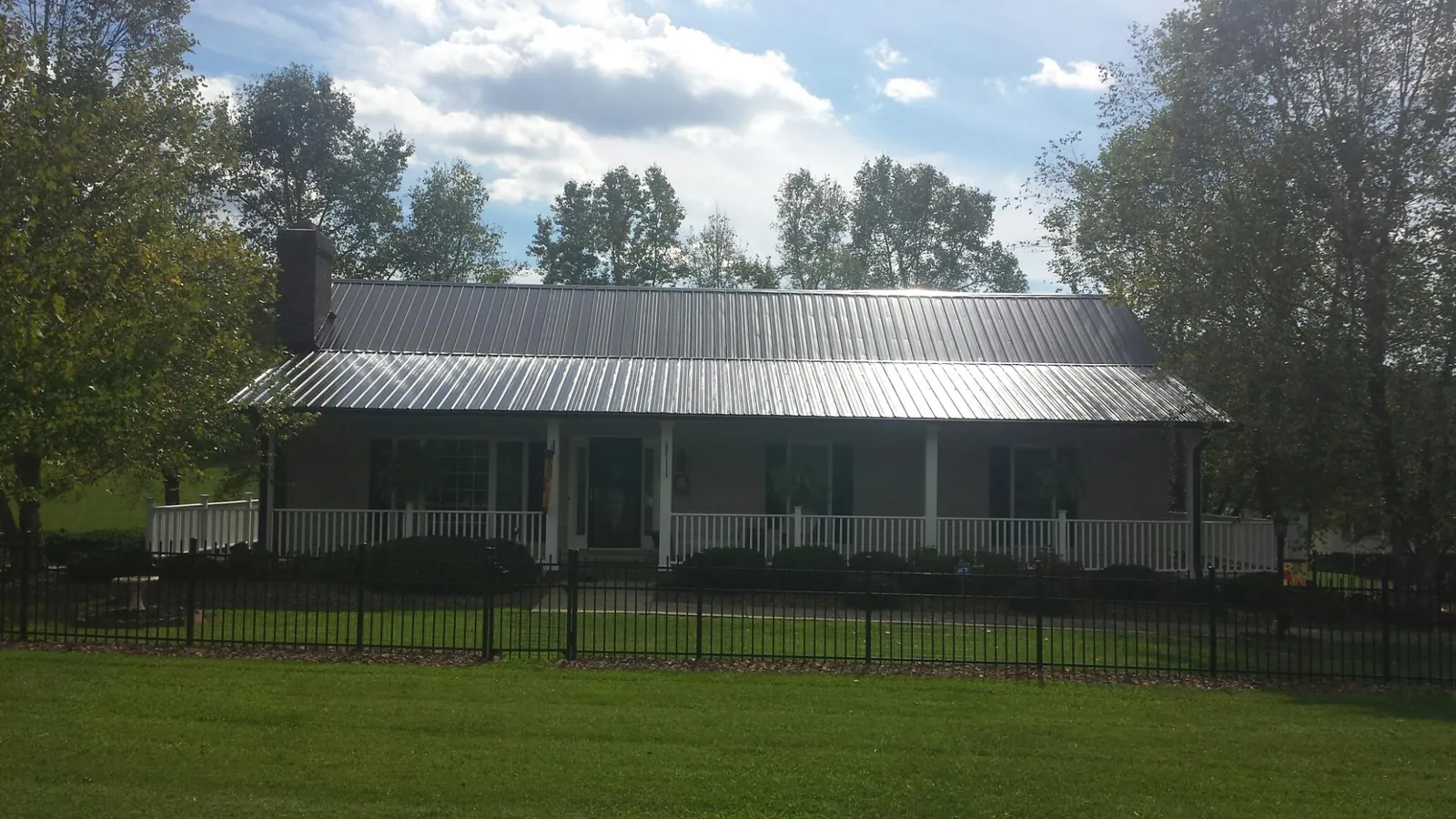 Gray metal roof on a brick ranch with a full width front porch — Gutter Guard Installation work by our crew in Myersville