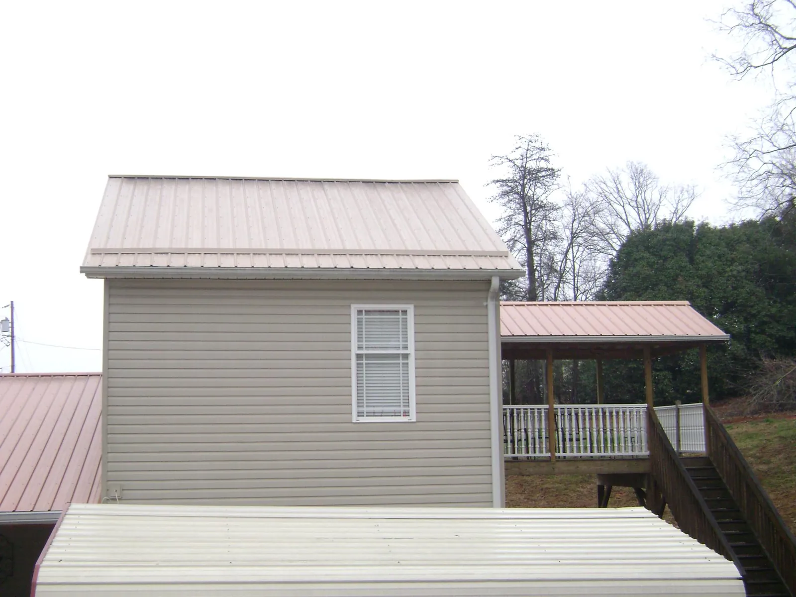 Tan metal roofs on a two story addition and attached porch, from a Roof Replacement job in Myersville