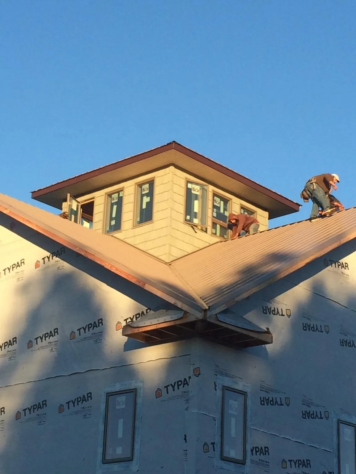 Roofers working around a rooftop cupola on a new metal roof at sunset — Roof Waterproofing in Myersville by Roofing Brothers